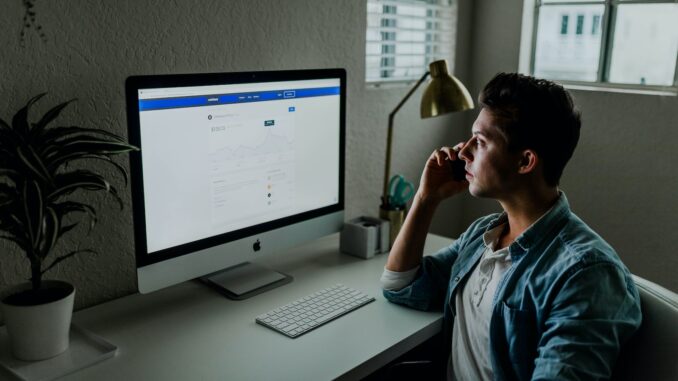 man in blue denim jacket facing turned on monitor