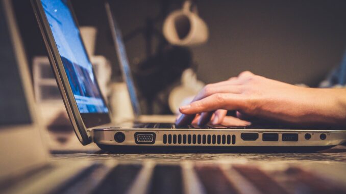 person using silver laptop computer on desk