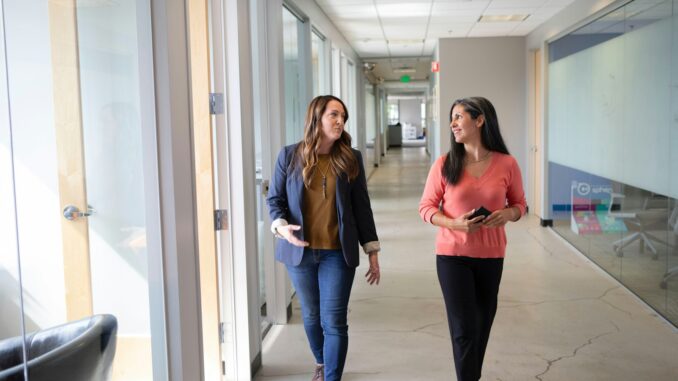 2 women standing near white wall