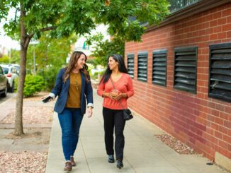 two women walking down a sidewalk talking to each other